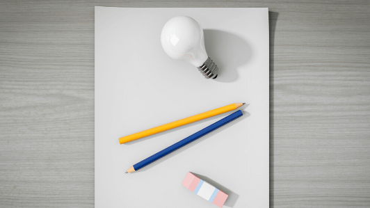 筆記用具と電球と紙